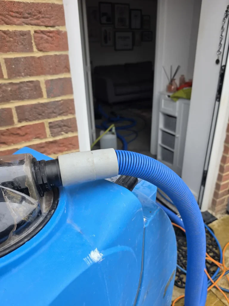 Blog 7 Blue AirFlex carpet cleaning machine outside a house with its hose running through the doorway