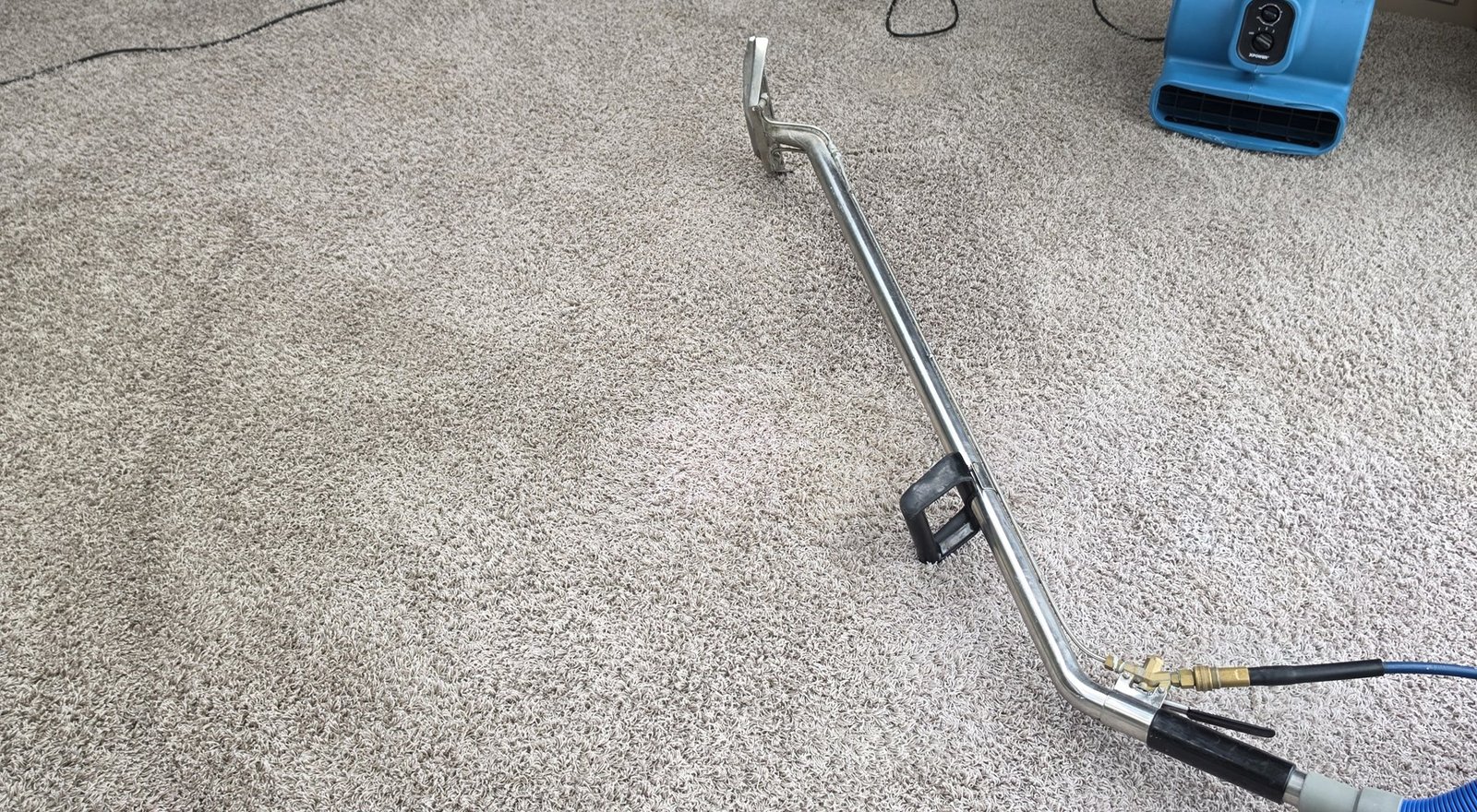 Carpet extraction wand and drying equipment on a grey carpet