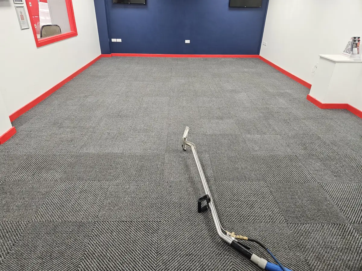 Extraction wand on grey commercial carpet tiles during a New Life Carpet cleaning visit