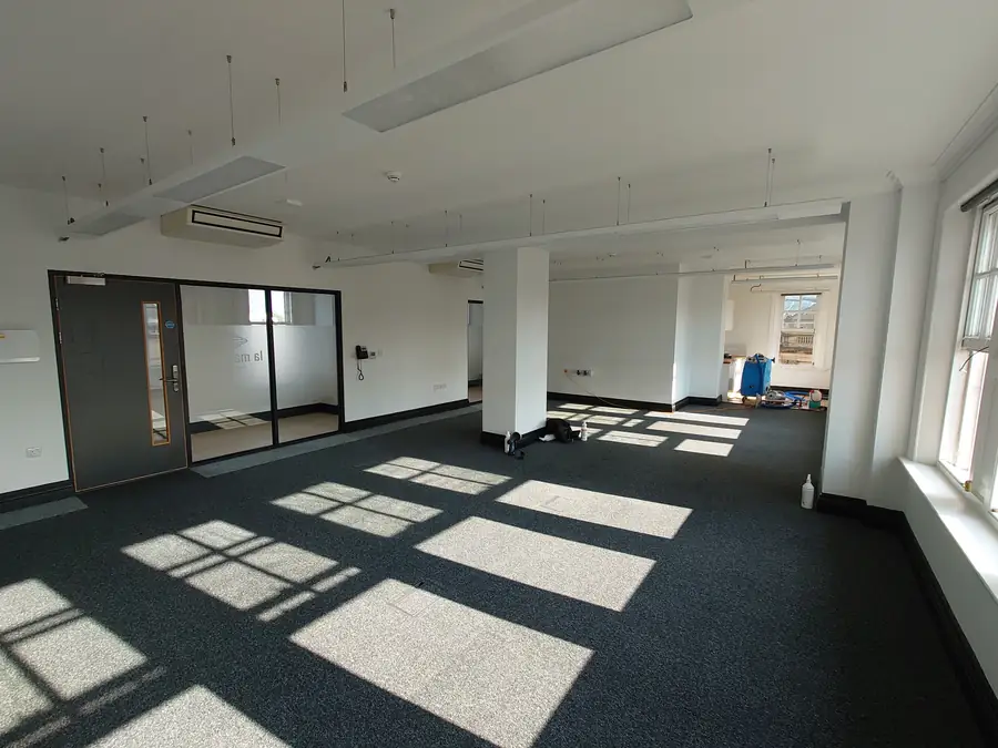 Carpeted open-plan office with glazed partitions and large windows