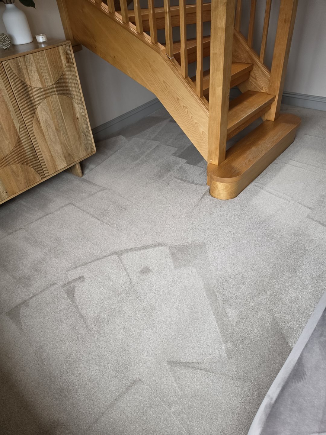 Freshly cleaned grey hallway carpet beside an oak staircase
