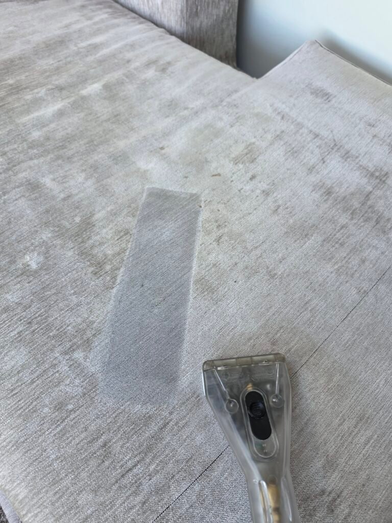Upholstery extraction tool cleaning a light grey carpeted stair tread