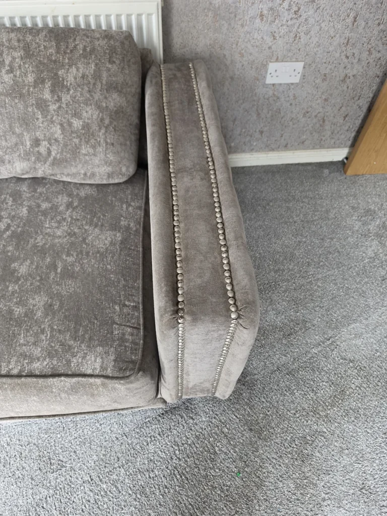Fabric sofa and carpet with a protective tab visible beneath a furniture foot