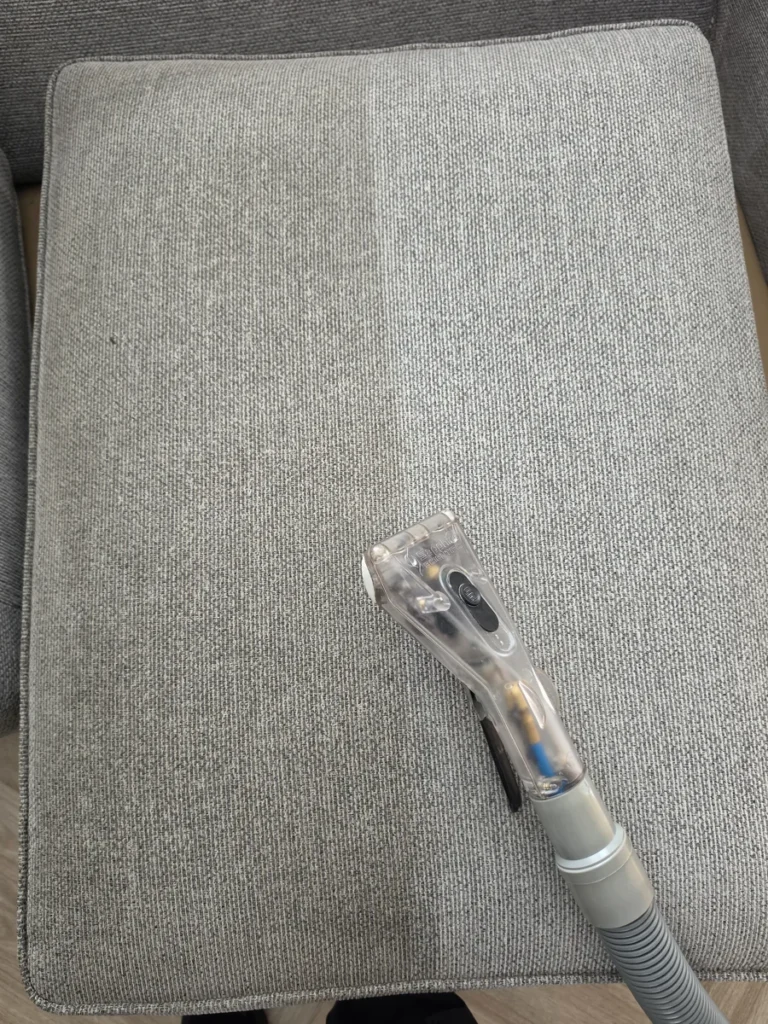 Upholstery extraction tool on a grey fabric cushion