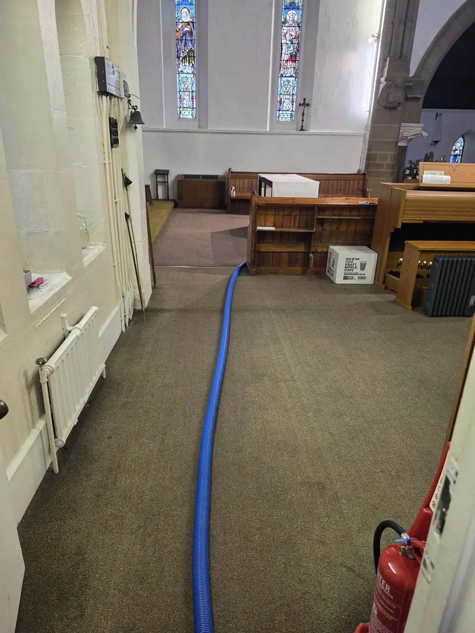 Carpet Cleaning at St Thomas Church of England 2 Cleaning hose along a carpeted side area beneath stained-glass windows inside St Thomas Church of England
